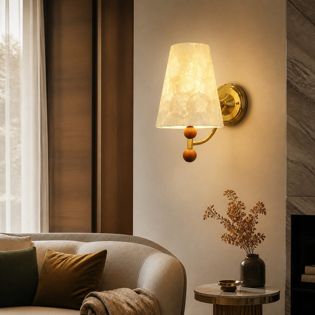 Warm Capiz shell wall light beside a curved sofa and stone fireplace