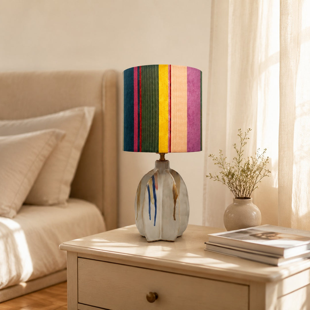 Striped fabric shade ceramic table lamp on a bedroom nightstand