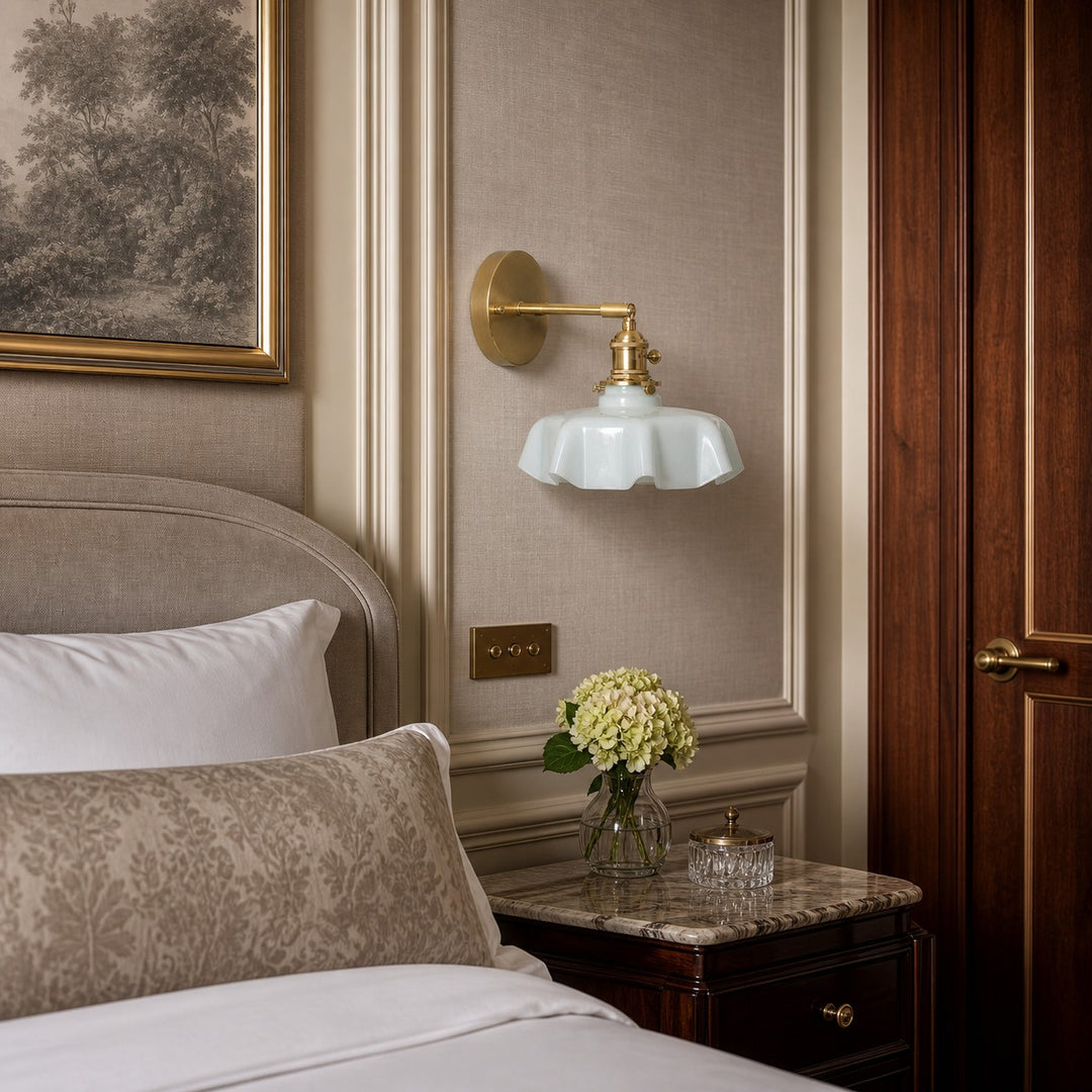 Blue milk glass brass wall sconce beside a bed