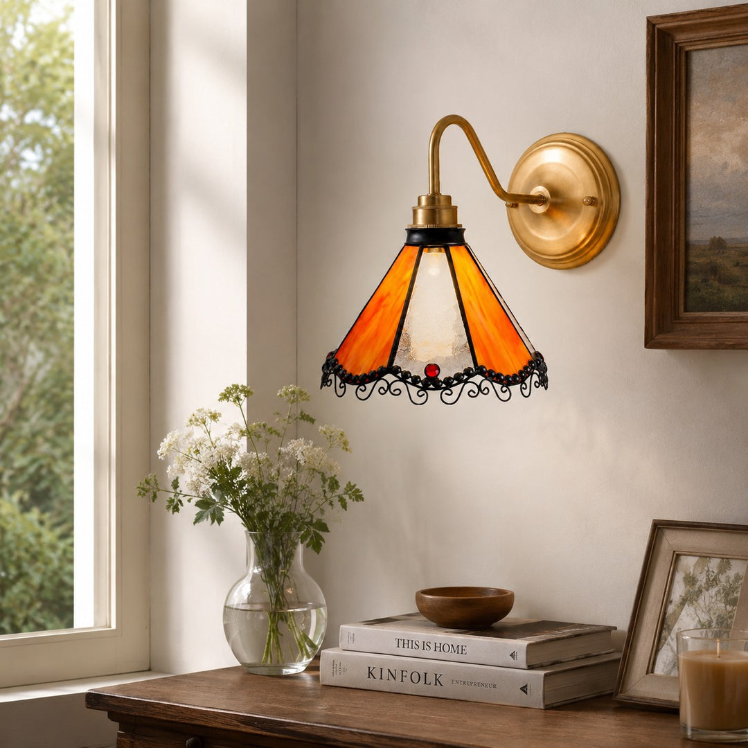 Orange stained glass wall sconce above a window console