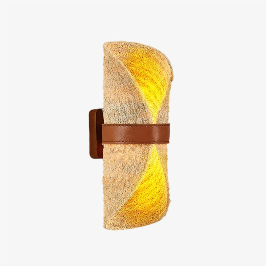 Beige natural loofah wall sconce with a brown leather band illuminated