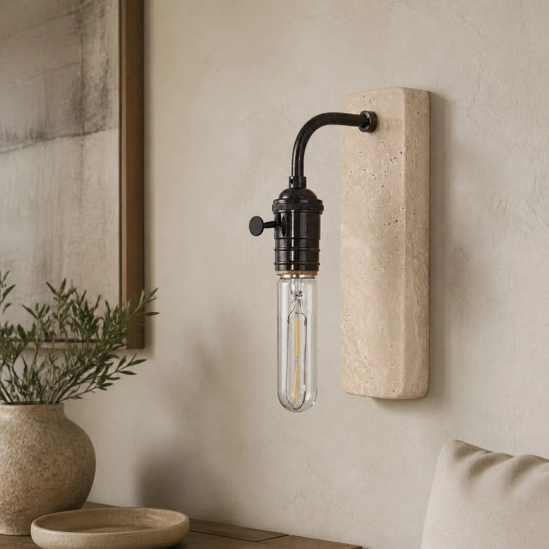 Black travertine wall sconce installed in a warm natural interior