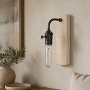 Black travertine wall sconce installed in a warm natural interior