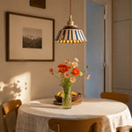 Load image into Gallery viewer, Striped ceramic pendant lamp above a round dining table with flowers