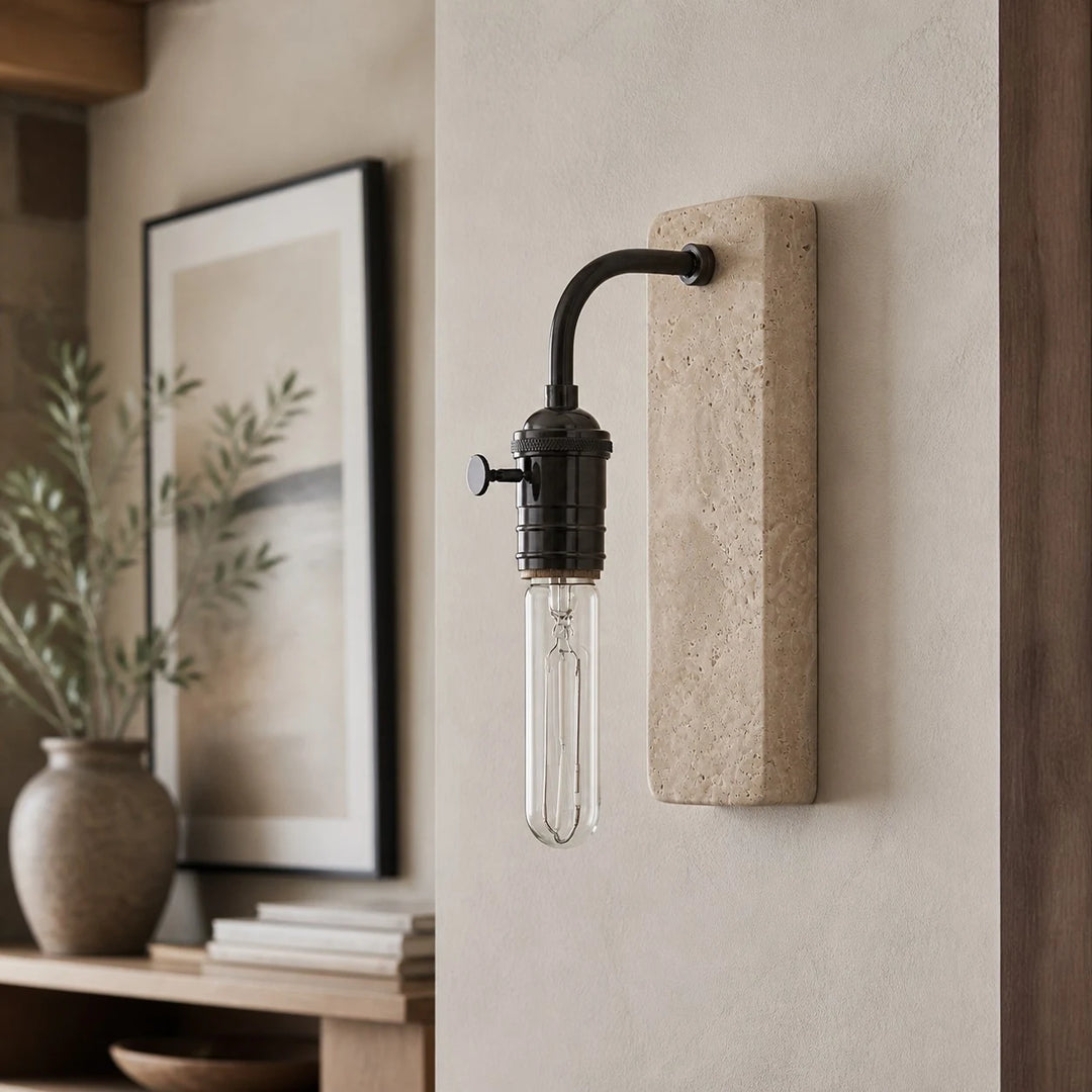 Black travertine wall sconce beside framed art and natural decor
