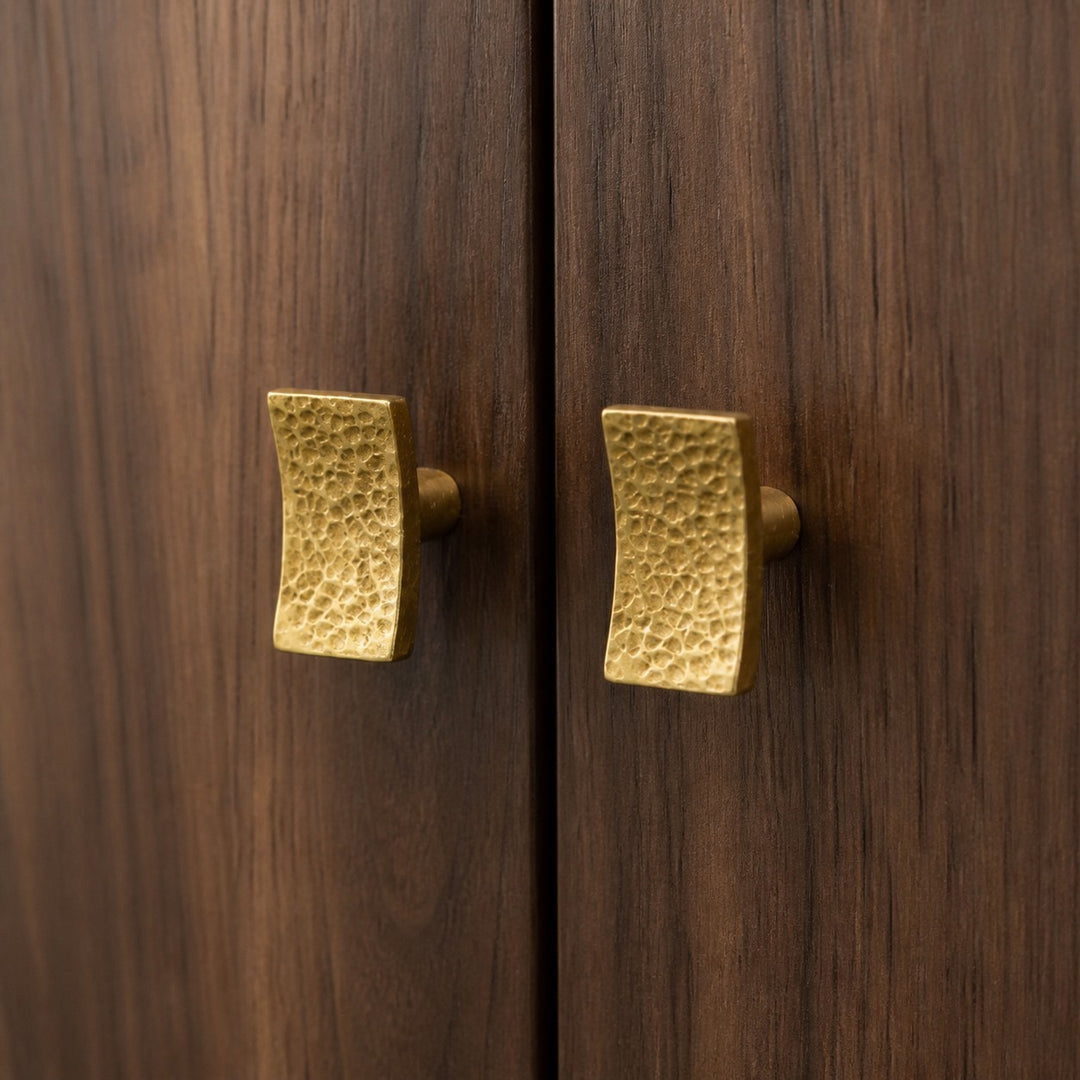 Hammered brass cabinet knobs installed on dark wood doors