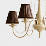 Bild in Gallery-Viewer laden, Close-up of cream iron chandelier body with curved arms and bead trim