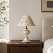 Capiz shell table lamp on a wooden bedside table in a warm bedroom