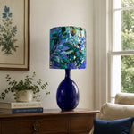 Load image into Gallery viewer, Green botanical fabric ceramic table lamp styled by a sofa