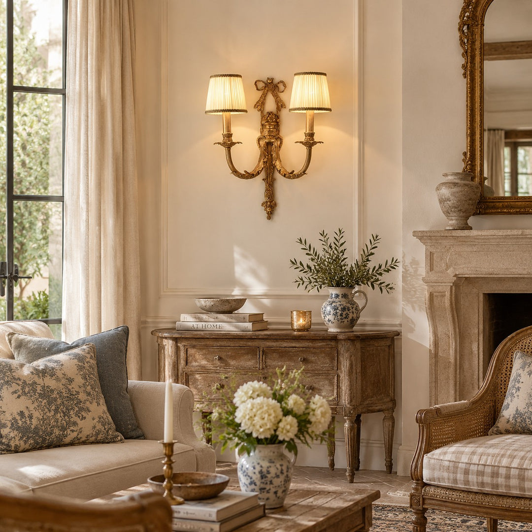 Two-head brass wall sconce with white shades in a refined living room