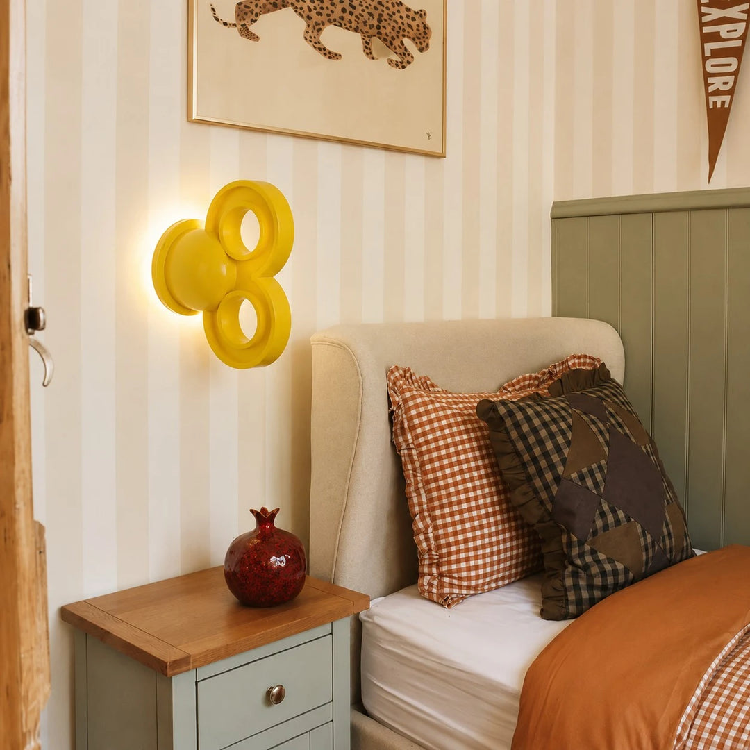Yellow wall light beside a bed in a warm bedroom