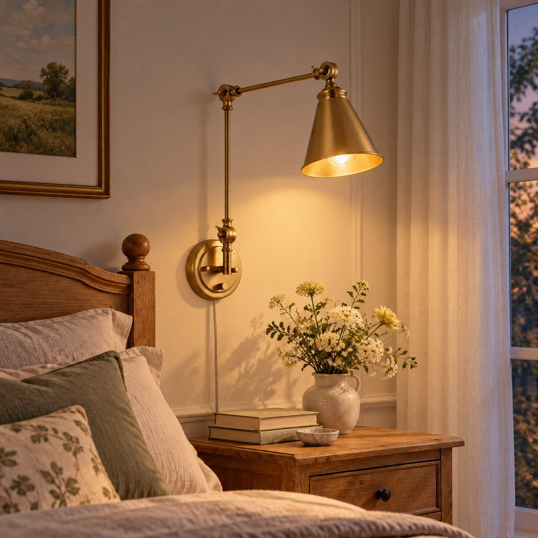 Gold swing-arm sconce glowing beside a bed at dusk