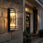 Cargar imagen en el visor de la Galería, Medium bronze glass outdoor wall sconce glowing on a stone exterior wall