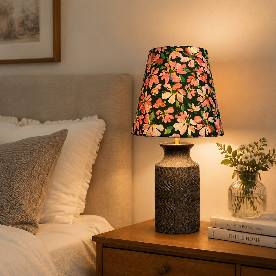 Floral ceramic bedside lamp glowing on a nightstand in a warm bedroom