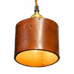 Bild in Gallery-Viewer laden, Close-up of brown leather cylinder shade with warm inner glow