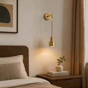 Pendant brass wall sconce installed beside a bed