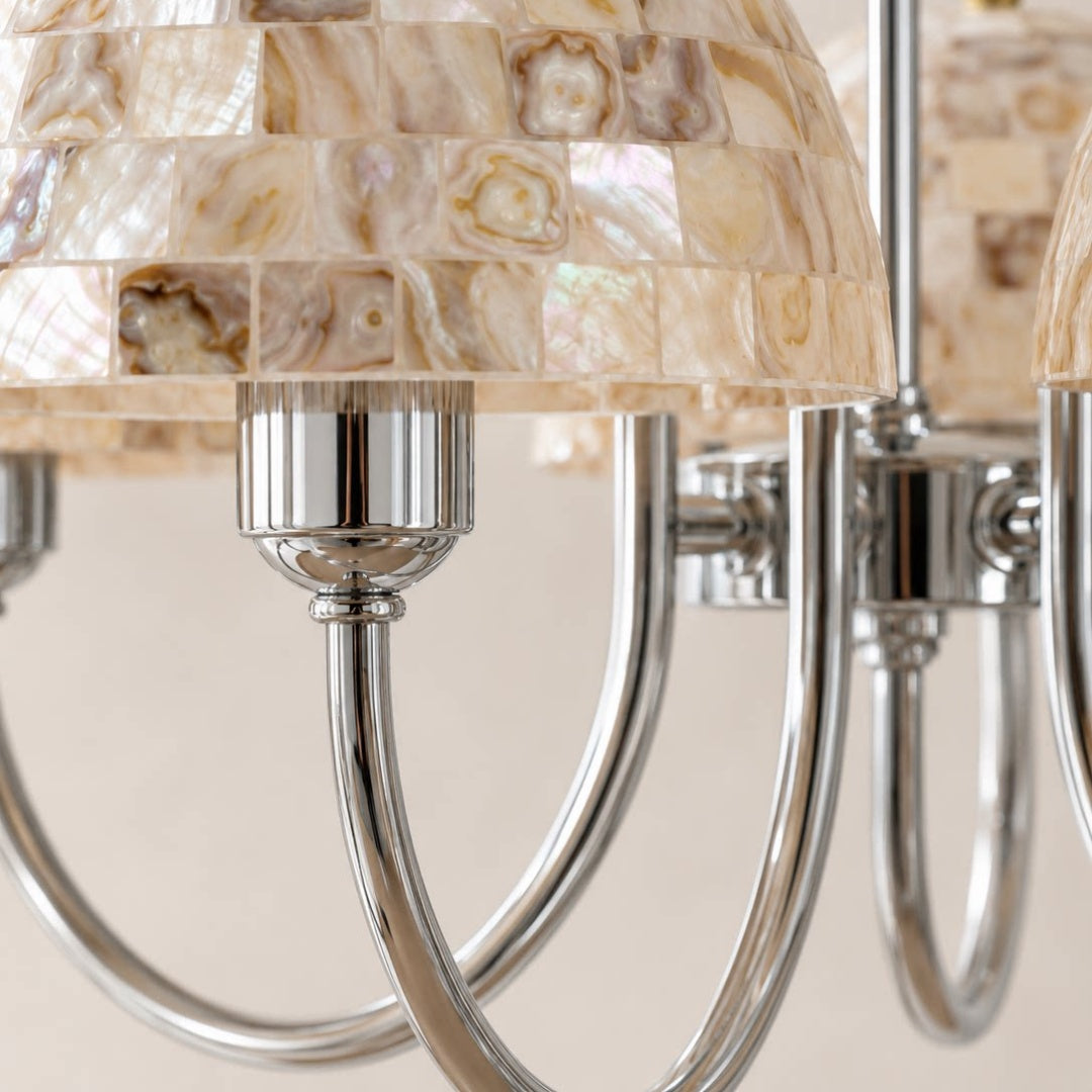 Close view of beige shell mosaic shades and polished metal chandelier arms