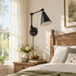 Load image into Gallery viewer, Black swing-arm sconce beside a bed in daylight