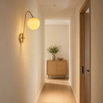 Load image into Gallery viewer, Brass glass wall light installed along a hallway wall