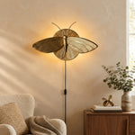 Charger l'image dans la visionneuse de galerie, Gold moth wall sconce glowing above a reading chair