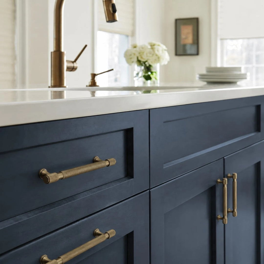 Antique brass pulls installed on blue kitchen cabinetry