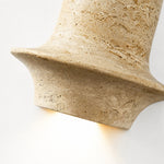 Charger l'image dans la visionneuse de galerie, Lit close view of travertine wall lamp showing warm downward glow and honed stone edge