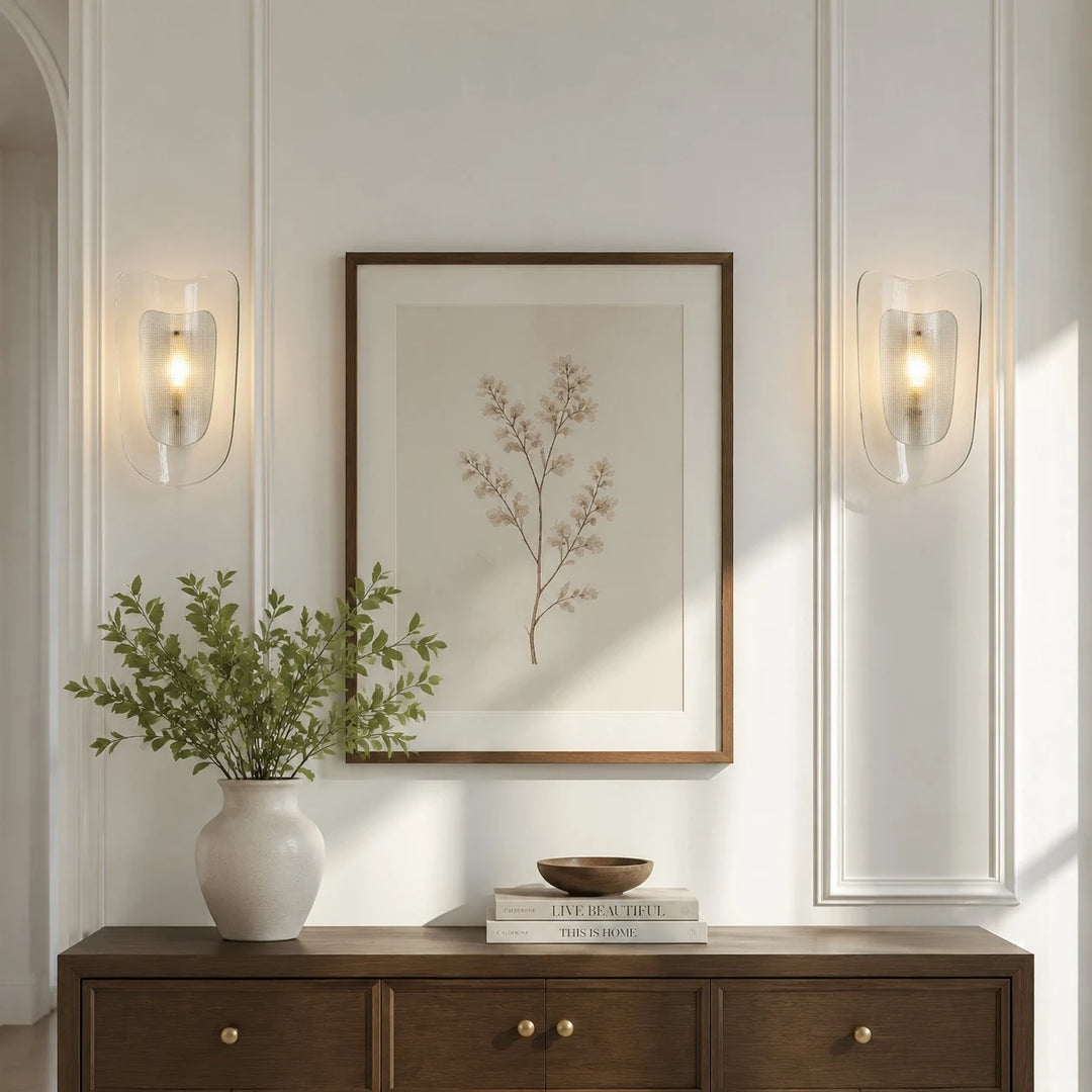 Clear glass wall sconce shown beside framed wall art