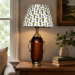 Load image into Gallery viewer, Deep brown floral table lamp glowing beside framed wall art