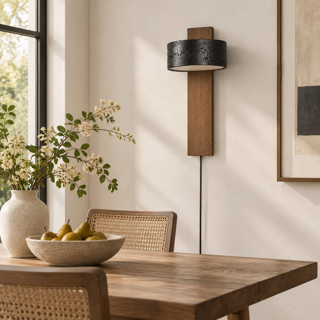 Walnut and black travertine wall sconce glowing in a living room