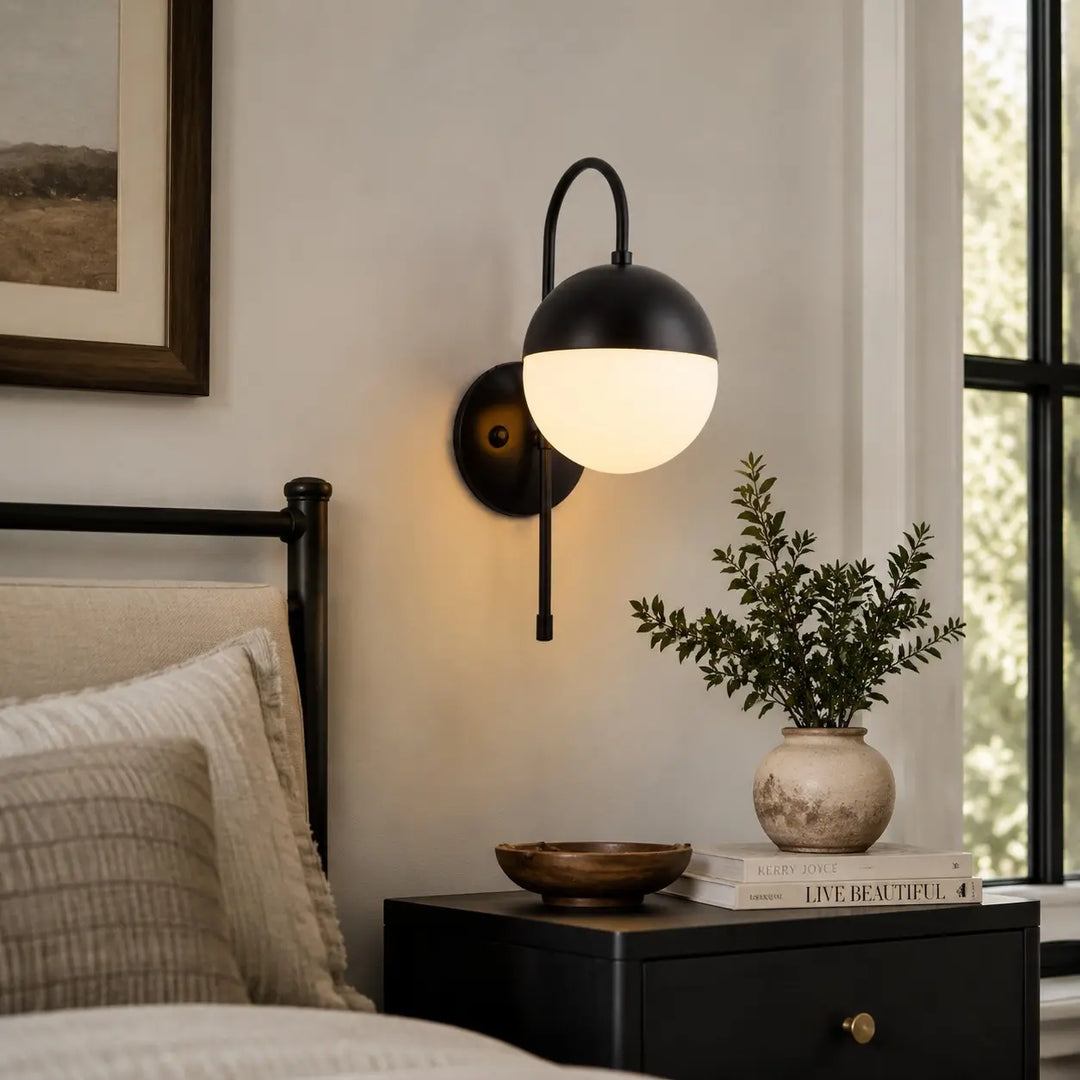 Black milk glass wall lamp beside a bed