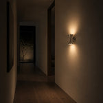 Charger l'image dans la visionneuse de galerie, Chrome wall sconce casting warm light in a quiet hallway