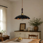 Load image into Gallery viewer, black cowhide pendant light casting warm light over a rustic table