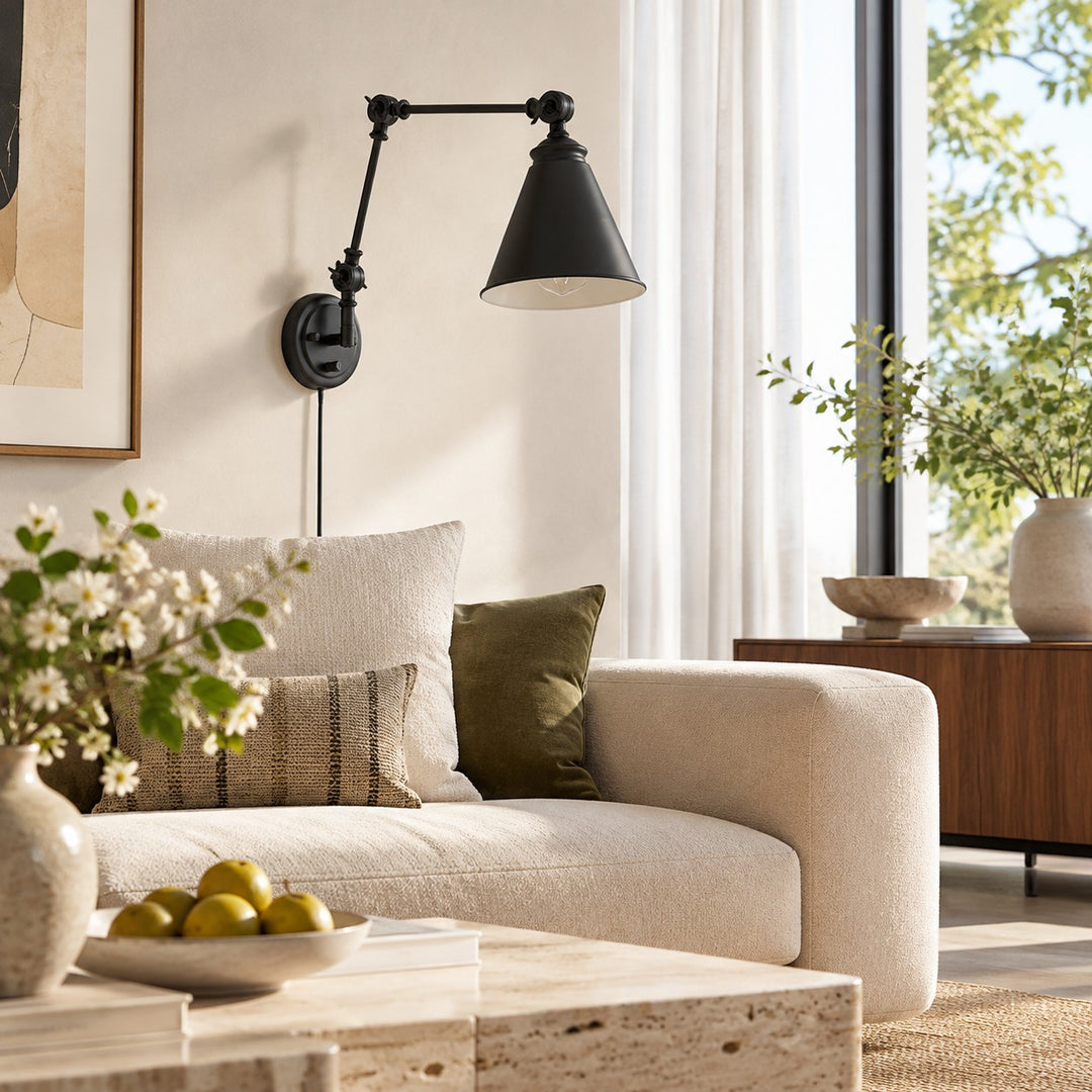 Black swing-arm sconce above a sofa in daylight