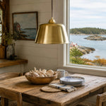 Load image into Gallery viewer, Bright brass pendant lamp above a coastal dining table