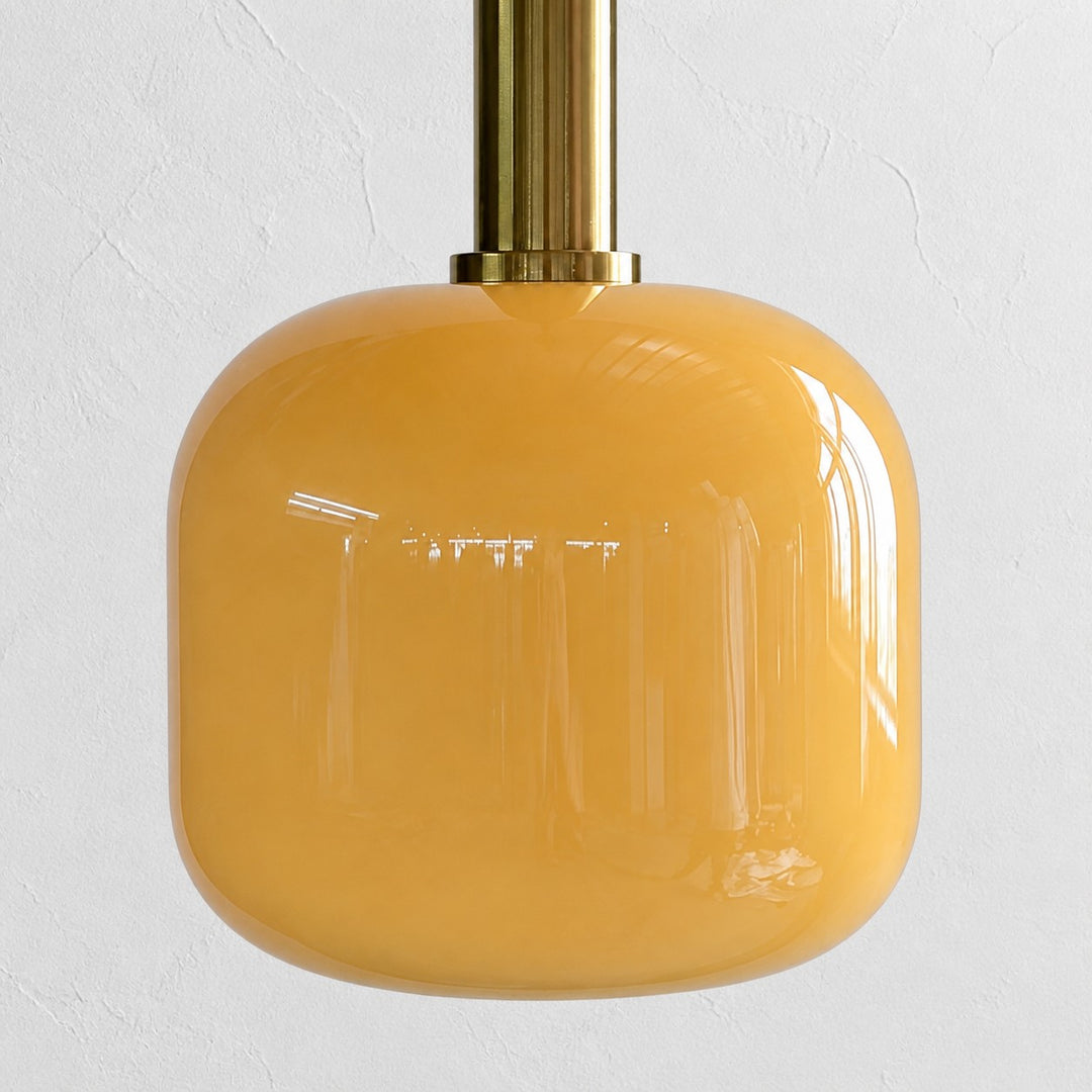 Close view of the rounded glossy yellow glass shade and brass holder