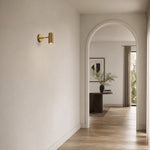 Load image into Gallery viewer, Brass cylinder wall sconce in a bright hallway