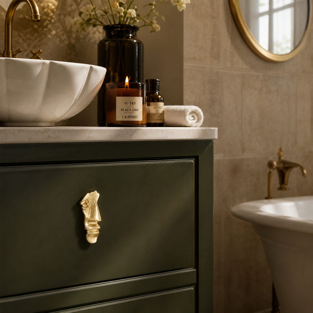Abstract brass face cabinet knob on a dark green bathroom drawer