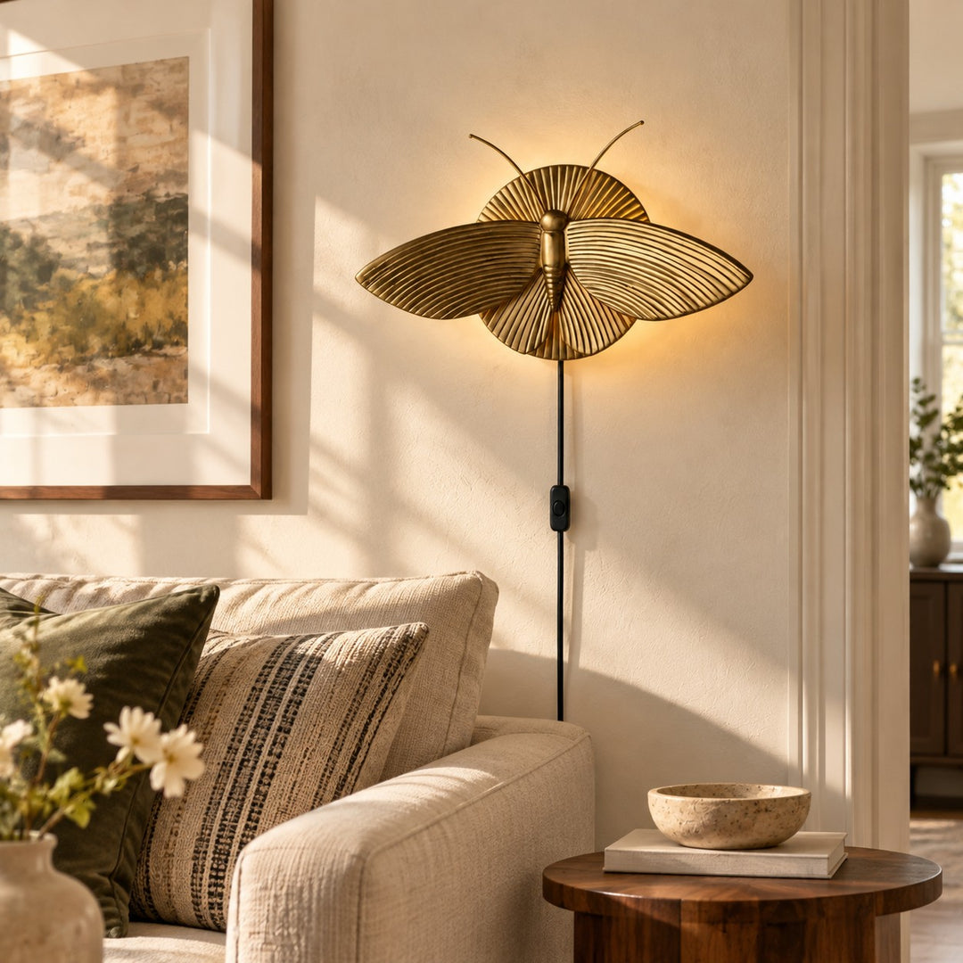 Gold moth wall sconce above a sofa in daylight