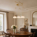 Load image into Gallery viewer, Gold three-light pendant above a dining table