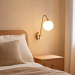 Load image into Gallery viewer, Brass glass globe wall light styled beside a bedroom wall