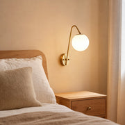 Brass glass globe wall light styled beside a bedroom wall
