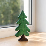 Green wooden pine tree ornament beside a window