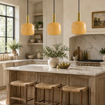 Bild in Gallery-Viewer laden, Yellow glass pendant lights over a kitchen island with brass accents