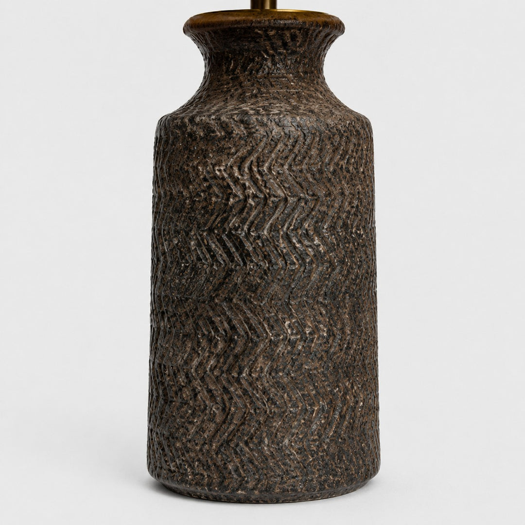 Close-up of carved wave texture on dark handmade ceramic lamp base