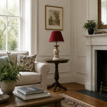 Load image into Gallery viewer, Red ceramic table lamp beside an armchair in daylight