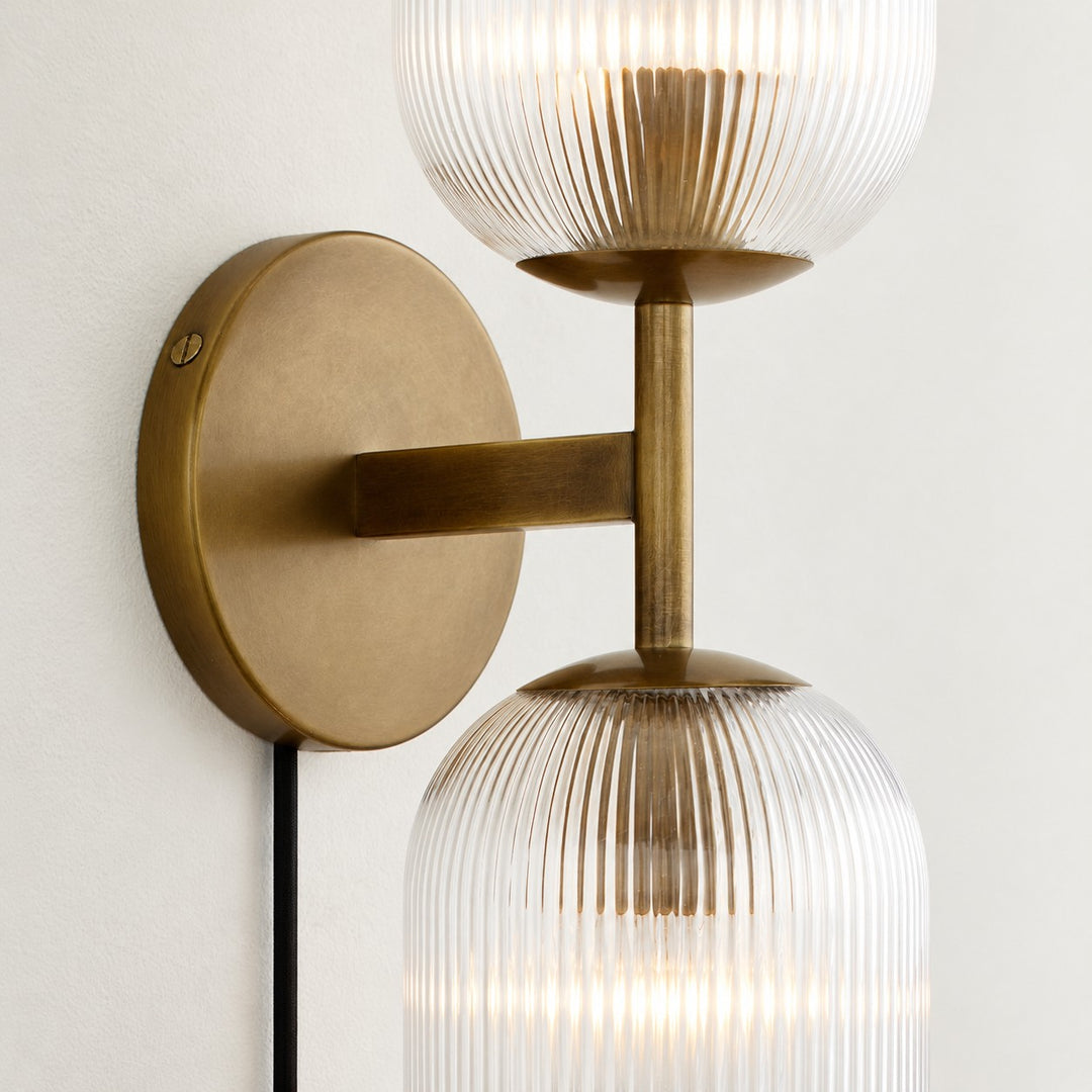 Close view of two tumbled-brass ribbed shades and the shared arm