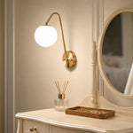 Load image into Gallery viewer, Brass globe wall light near a vanity and table setting