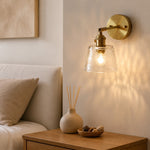 Load image into Gallery viewer, Clear brass glass wall sconce beside a bed