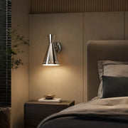 Polished cone wall sconce installed beside a bed