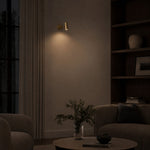 Load image into Gallery viewer, Brass cylinder wall sconce casting downward light in a quiet evening living room